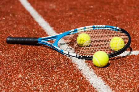 Time to play tennis. Close-up of tennis racket and three tennis balls laying on the court 