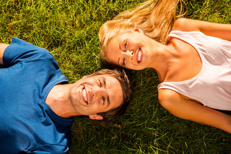 We love summer! Top view of happy young loving couple lying on the green grass together and smilingの写真素材