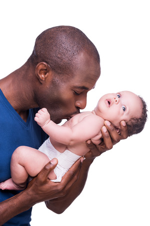 My baby! Young African man holding his little baby and kissing him while standing isolated on whiteの写真素材