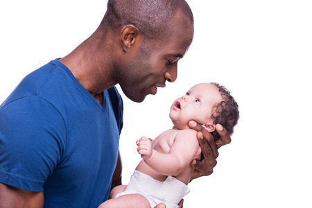 That is my boy! Side view of happy young African man holding his little baby and looking at him while standing isolated on whiteの写真素材