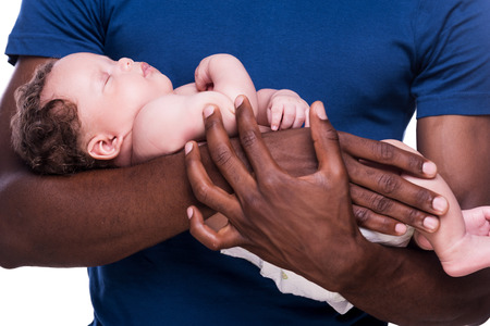 Father and son. Close-up of African man holding his little baby while standing isolated on whiteの写真素材