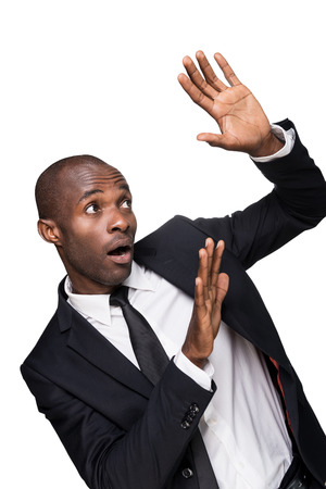 Please no! Terrified young African man in formalwear looking up and gesturing while standing isolated on white backgroundの写真素材
