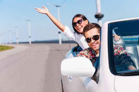 Traveling with fun. Happy young couple enjoying road trip in their white convertible 