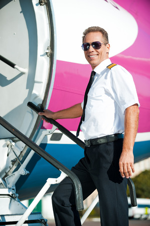 Ready to flight! Confident male pilot in uniform going into the airplane and smilingの写真素材