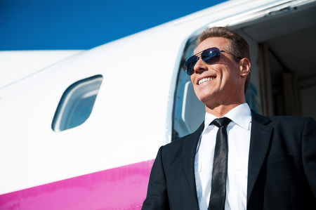 Here I am! Low angle view of confident mature businessman getting out of airplane and smilingの写真素材