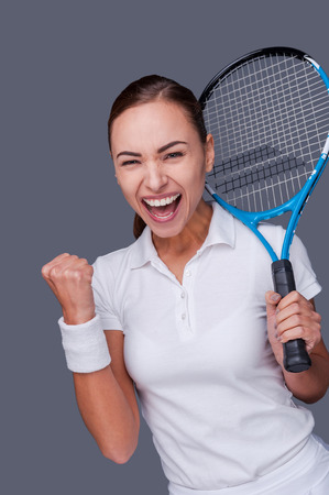 Victory is in my pocket! Portrait of a beautiful young woman cheering while holding her tennis racket on her shoulderの写真素材