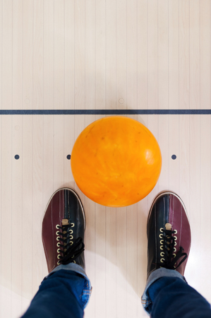 Close-up of a bowling ball lying near human legsの写真素材