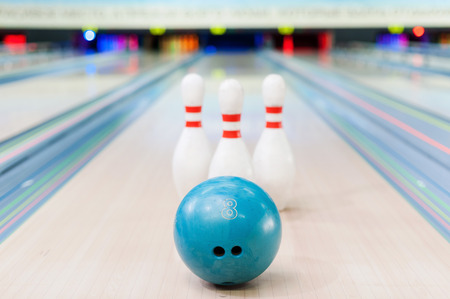 Close-up of blue bowling ball lying against pins staying on bowling alleyの写真素材