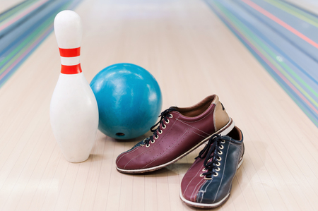 Close-up of bowling shoes, blue ball and pin lying on bowling alleyの写真素材