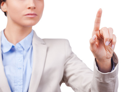 Touching new reality. Close-up of young businesswoman touching a transparent wipe board while standing against white backgroundの写真素材