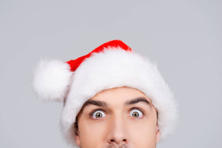 No way! Surprised young man in Santa hat staring at you while standing against grey backgroundの写真素材