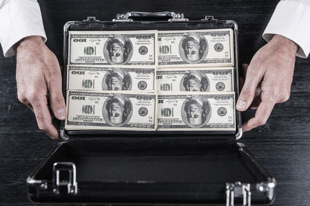 Lots of money. Top view of man opening a briefcase full of paper currencyの写真素材
