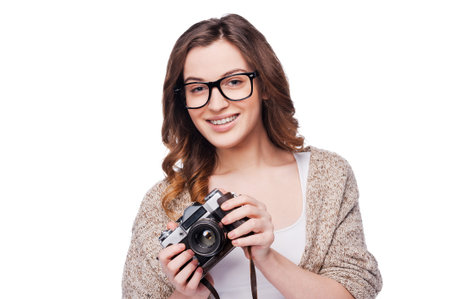 Beautiful photographer. Attractive young smiling woman holding camera while standing isolated on...
