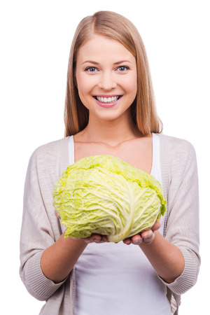 Useful vegetable. Beautiful young woman holding cabbage and smiling while standing against white backgroundの写真素材