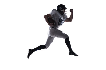 Side view of American football player holding ball and jumping against white backgroundの写真素材