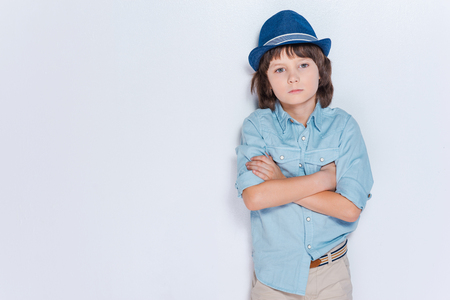 Full of inspiration.  Little boy wearing hat and keeping arms crossed while standing against white backgroundの写真素材