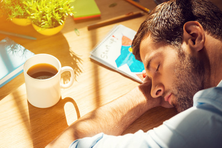 Giving all his energy to work. Close-up top view of tired man sleeping while sitting at his working placeの写真素材