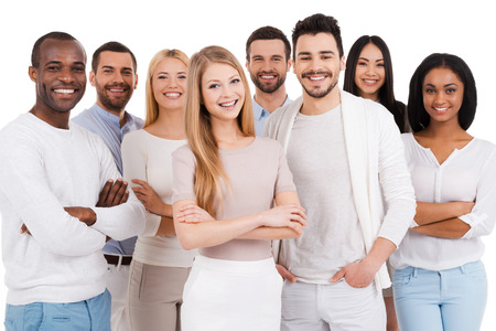 Positive professional team. Group of positive and diverse people in smart casual wear looking at camera and smiling while standing against white background Positive professional team. Group of positive and diverse people in smart casual wear looking at camera and smiling while standing against white background