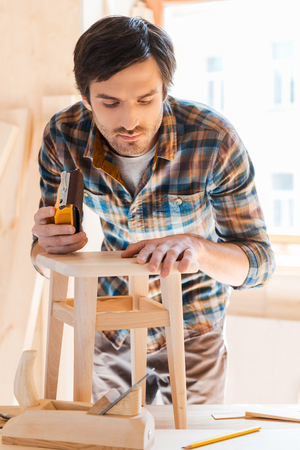 Working with wood is his passion. Concentrated young male carpenter working in his workshopの写真素材