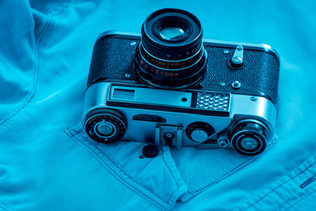 Retro styled camera. Close-up of retro camera laying on blue shirt