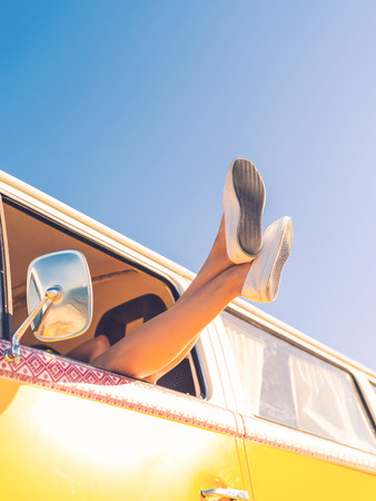 Full freedom and relaxation. Low angle view of woman stretching out her legs out of the window while sitting inside of minivanの写真素材