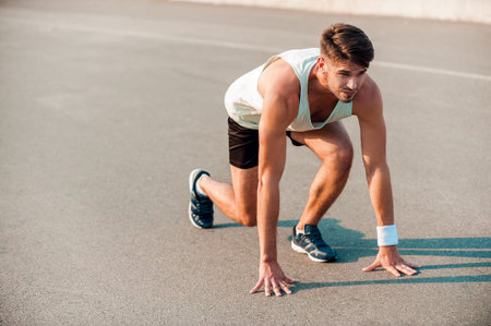 Total concentration. Confident young muscular man standing in starting line and looking forward