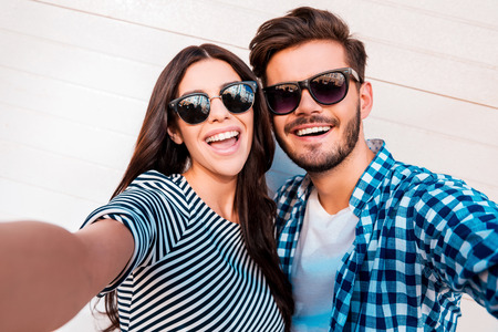 Capturing bright moments. Joyful young loving couple making selfie on camera while standing outdoorsの写真素材