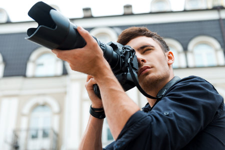 Taking a perfect shot. Low angle view of young man photographing something while standing outdoors