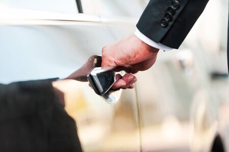 His business car. Close-up of businessman holding hand on door handle while opening his carの写真素材