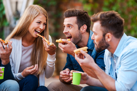Pizza lovers. Group of playful young people eating pizza while having fun together Pizza lovers. Group of playful young people eating pizza while having fun together