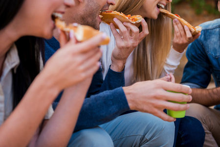 Time for pizza! Group of young people eating pizza while sitting outdoors Time for pizza! Group of young people eating pizza while sitting outdoors
