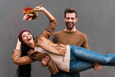 Love and fun. Beautiful young couple having fun together while standing against grey wallの写真素材