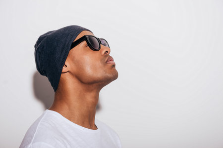 What is that? Side view of handsome young African man in headwear looking up while standing against...