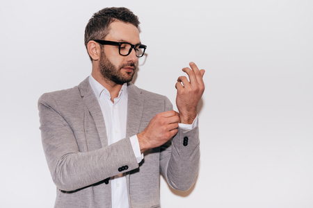 Everything should be perfect. Confident mature man in smart casual wear adjusting his sleeve while standing against white backgroundの写真素材