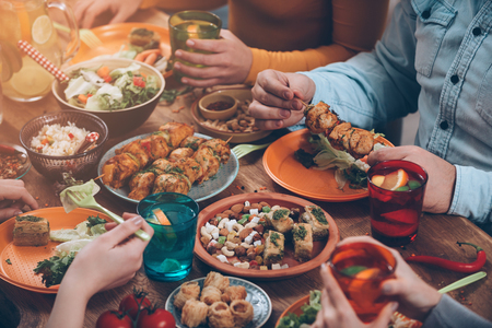 Friendly dinner. Top view of group of people having dinner together while sitting at the rustic wooden table Friendly dinner. Top view of group of people having dinner together while sitting at the rustic wooden table