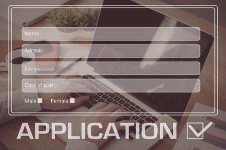 Apply online. Close-up top view of man working on laptop with digitally composed application form over itの写真素材