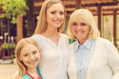 Female part of family. Three generations of family women bonding to each other and smiling while...