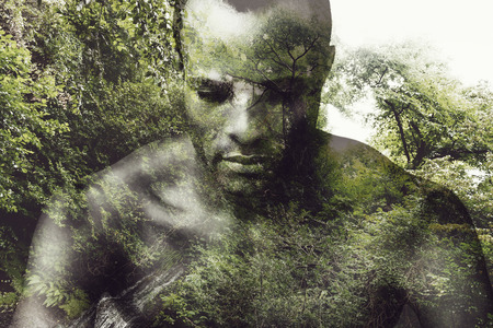 Deeper in nature. Digitally composed picture of shirtless young African man keeping eyes closed over the picture of green forestの写真素材