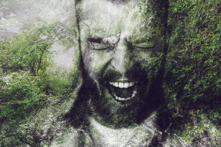 Furious man. Digitally composed image of furious young bearded man keeping mouth open and eyes closed over the picture of green forestの写真素材