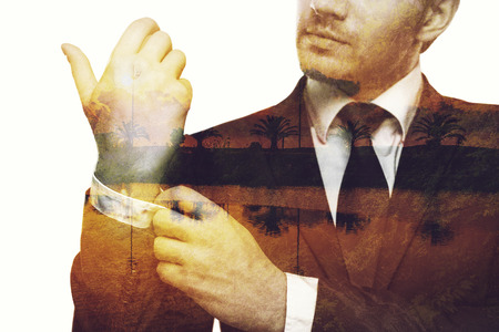 Popping memories. Digitally composed close-up picture of young businessman adjusting his sleeve over the picture of landscape with palm treesの写真素材