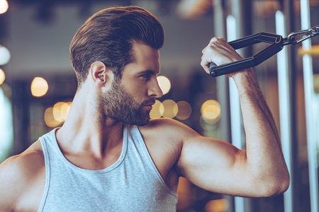 Working with bicep. Close up of young man in sportswear exercising at gym