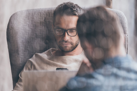 Working moments. Close-up of handsome man using his laptop while sitting in chairの写真素材