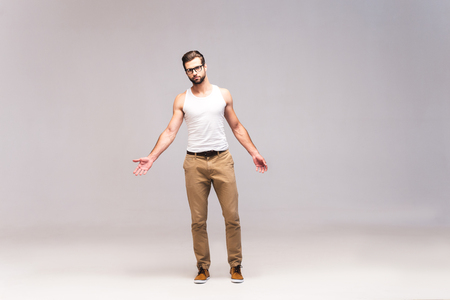 Staying casual. Full length studio shot of handsome young man in casual wear looking at camera and stretching out handsの写真素材