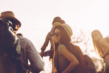 Travelling with friends. Group of young people with backpacks walking together and looking happyの写真素材