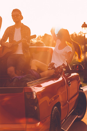 Enjoying perfect road trip. Beautiful young couple enjoying road trip while sitting in pick-up truckの写真素材