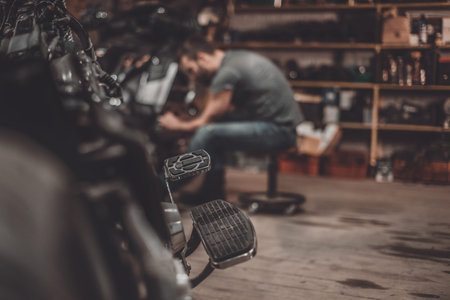 Repairing bike. Confident young man repairing motorcycle in repair shop