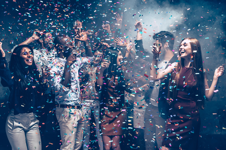 Confetti fun. Group of beautiful young people throwing colorful confetti and looking happy while bonding to each otherの写真素材