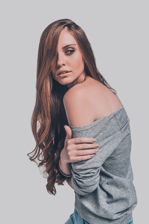 Elegance and beauty. Studio shot of attractive young woman in casual wear showing her shoulder and looking over itの写真素材