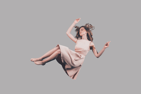 Falling in motion. Studio shot of attractive young woman hovering in airの写真素材