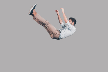 Free falling. Mid-air shot of handsome young man falling against grey backgroundの写真素材
